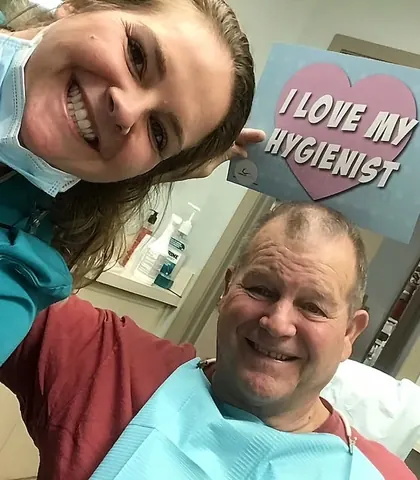 A hygienist and a smiling patient holding an I love my hygienist sign.