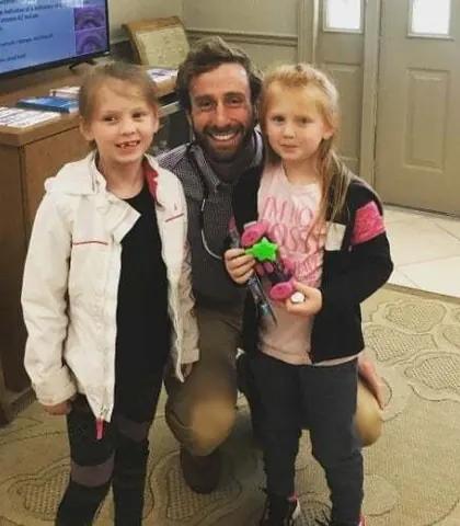 Dr. MacKenzie Farnham kneeling with two young patients in the waiting room.